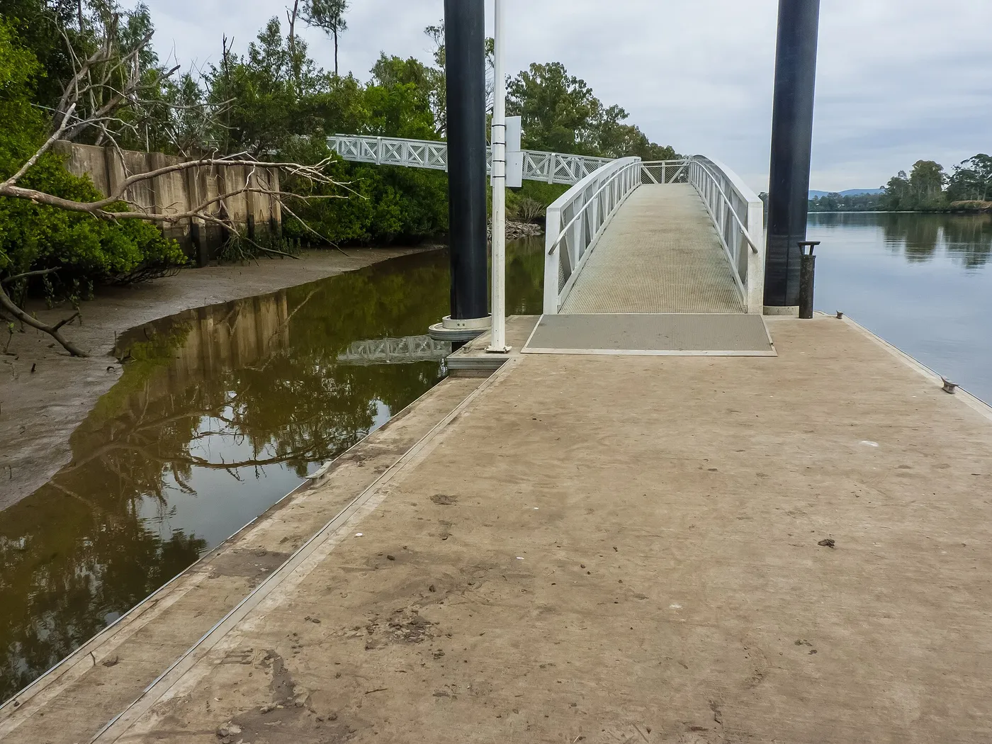 Aluminum truss gangway landing on a floating pontoon with transition plate and pile guides