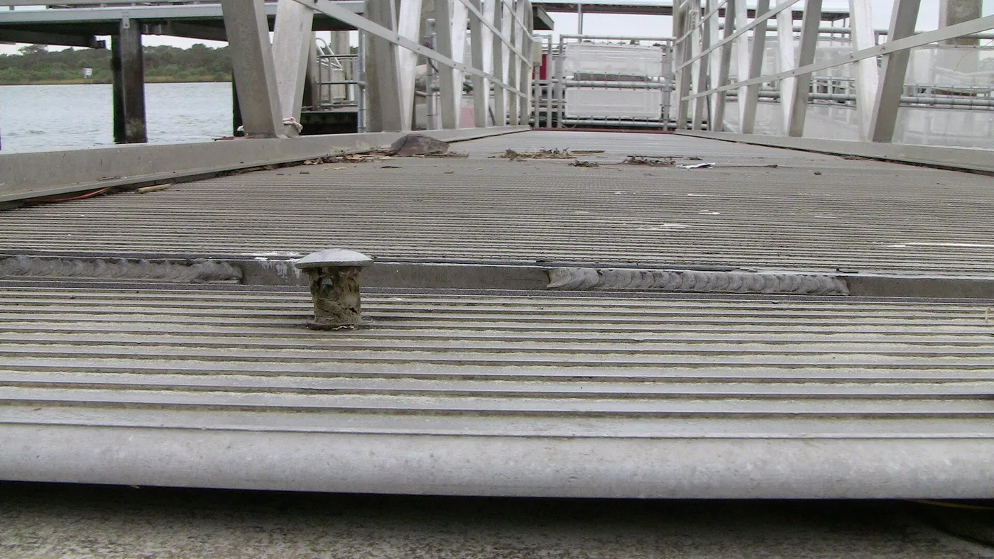 Aluminum gangway transition plate damaged by storm surge stress on a floating dock